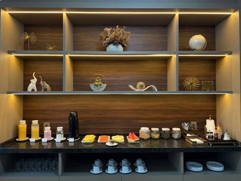 Estante com garrafas, geleias e as louças do café
