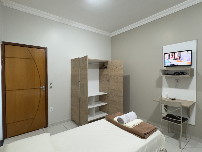 Cama de solteiro, guarda-roupa e televisão