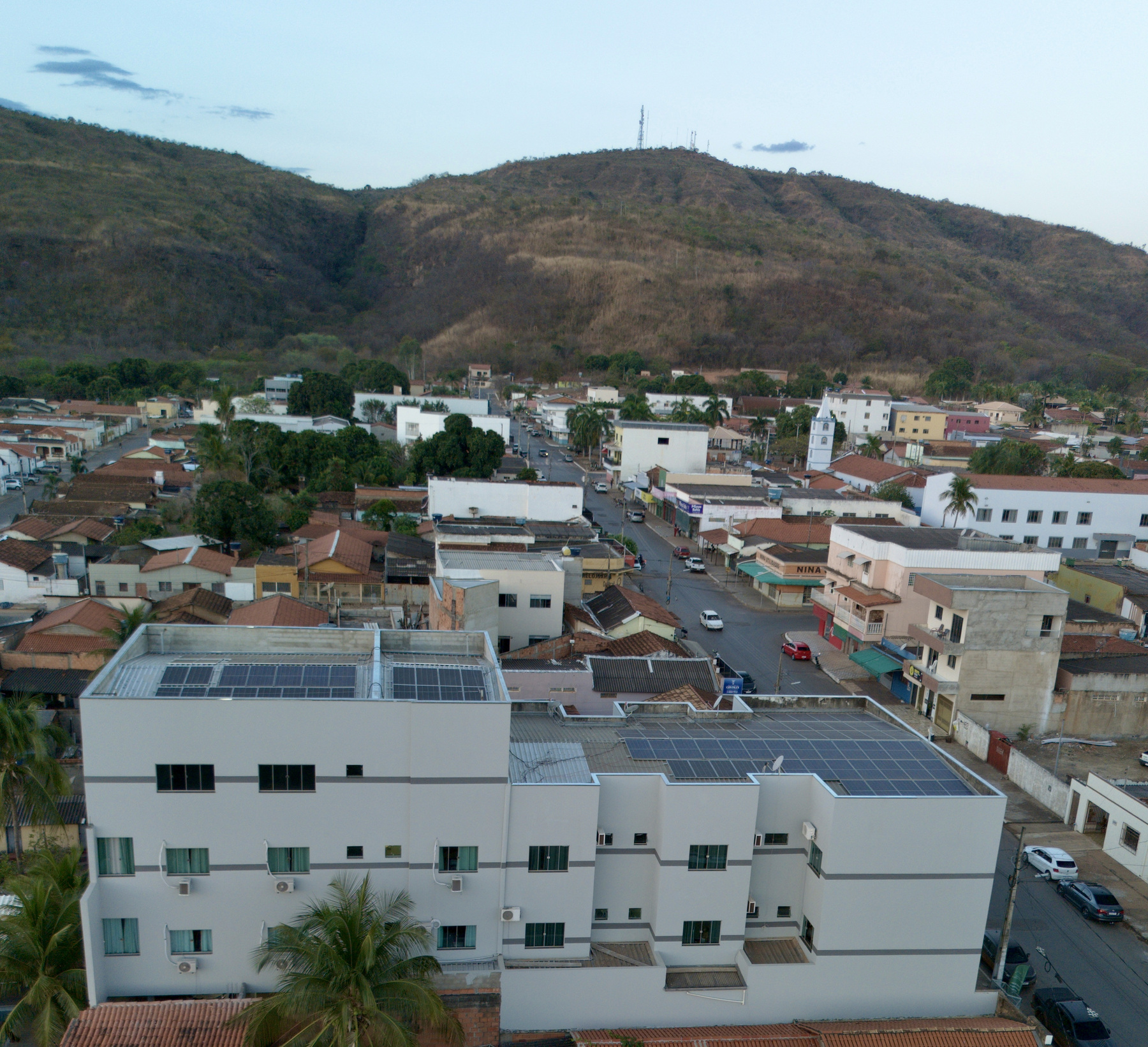 O hotel visto do outro lado, com a rua do centro e a serra ao fundo
