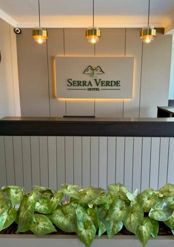 Recepção vista de frente, com o logotipo iluminado e a jardineira
