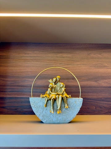 Escultura dourada de um casal, sobre a estante